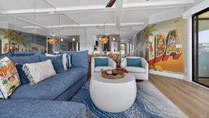 Un salon moderne avec un canapé bleu, un fauteuil blanc et une table basse ronde.