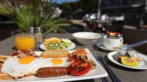 A breakfast table with eggs, sausages, toast, tomatoes, and a cup of coffee. - Oceanview 1 Bed Apartment @ Quality Resort Sorrento Beach (Sorrento)