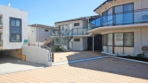 Un edificio residencial moderno con una escalera central, un espacio exterior cubierto y un cielo despejado.