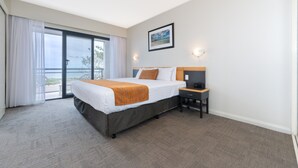 Habitación de hotel con cama, mesita de noche, escritorio y un amplio ventanal con vistas.