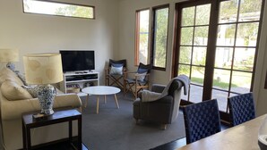 Una sala de estar con un sofá, sillones, un televisor y una mesa de comedor.