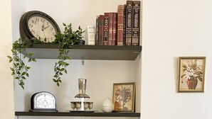 Ein Bücherregal mit verschiedenen Dekorationselementen, darunter Bücher, eine Uhr und Vasen.
