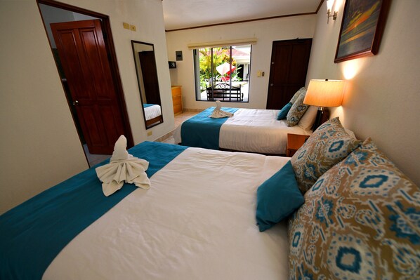 A hotel room with two beds, a window with a view of the outdoors, and a door.
