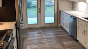 A kitchen with a double-door glass entry, a refrigerator, an oven, and a dishwasher.