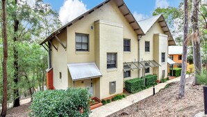 A two-story residential building with a flat roof, multiple windows, and a small porch area.