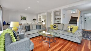 Un salon moderne avec un canapé gris, une table basse en verre et un plancher en bois.