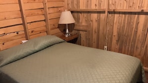 Una stanza con un letto, un comodino e una parete in legno.