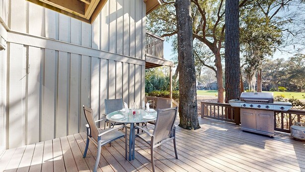 A deck with a glass table and chairs, a barbecue grill, and a wooden fence. - Very peaceful and tranquil setting. (Hilton Head)