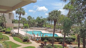 A pool area with a clear view of the pool, surrounding palm trees, and a pathway leading to the pool.