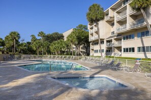 A hotel with a swimming pool, lounge chairs, and palm trees. - Oceanfront condo, Two Bedroom, Second Floor (Hilton Head)
