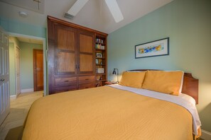 A bedroom with a large bed, wooden wardrobe, and a framed picture on the wall.