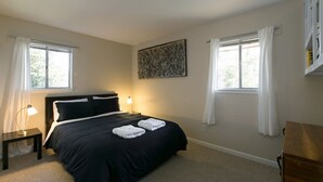 Un dormitorio con una cama, dos mesitas de noche, una lámpara y un cuadro en la pared.