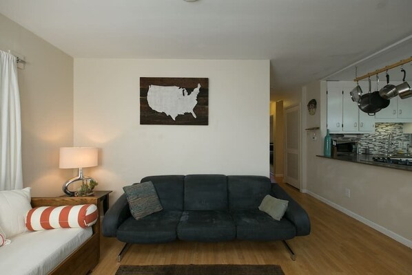 A living room with a dark sofa, a lamp, and a wall-mounted map.