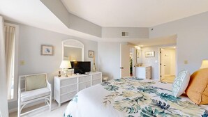 Een hotelkamer met een bed, een televisie, een dressoir, een stoel en een spiegel.