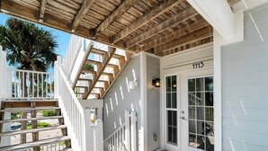 A wooden deck with a white railing, a door marked "1113", and a small porch area with a lantern. - Updated 2 BR! Breathtaking View of the Gulf Sunsets! B1113A (Cape Haze)
