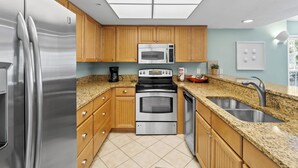 A modern kitchen with wooden cabinets, stainless steel appliances, a granite countertop, and a skylight. - Updated 2 BR! Breathtaking View of the Gulf Sunsets! B1113A (Cape Haze)