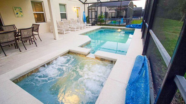 A swimming pool with a hot tub, lounge chairs, and a covered patio area. - Executive 5 Bed 4.5 Bath Vacation Home W/ Pool, Spa Near Disney  (Kissimmee)