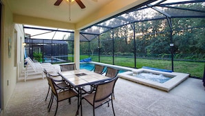 A covered patio with a pool table, chairs, and a hot tub. - Executive 5 Bed 4.5 Bath Vacation Home W/ Pool, Spa Near Disney  (Kissimmee)