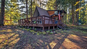 A cabin with a wooden deck, a staircase, and a view of the forest. - Serene Washington Escape w/ Deck & Mountain Views! (Packwood)