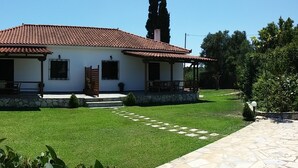 Ein zweistöckiges Haus mit rotem Ziegeldach, Steinuntergrund und gepflegtem Rasen.