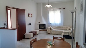 Ein Wohnzimmer mit Kamin, Sofa, Esstisch und Lampe.