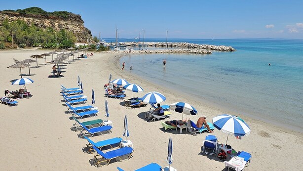 Ein Strand mit blauen und weißen Streifenmustern an Sonnenschirmen und Liegestühlen.
