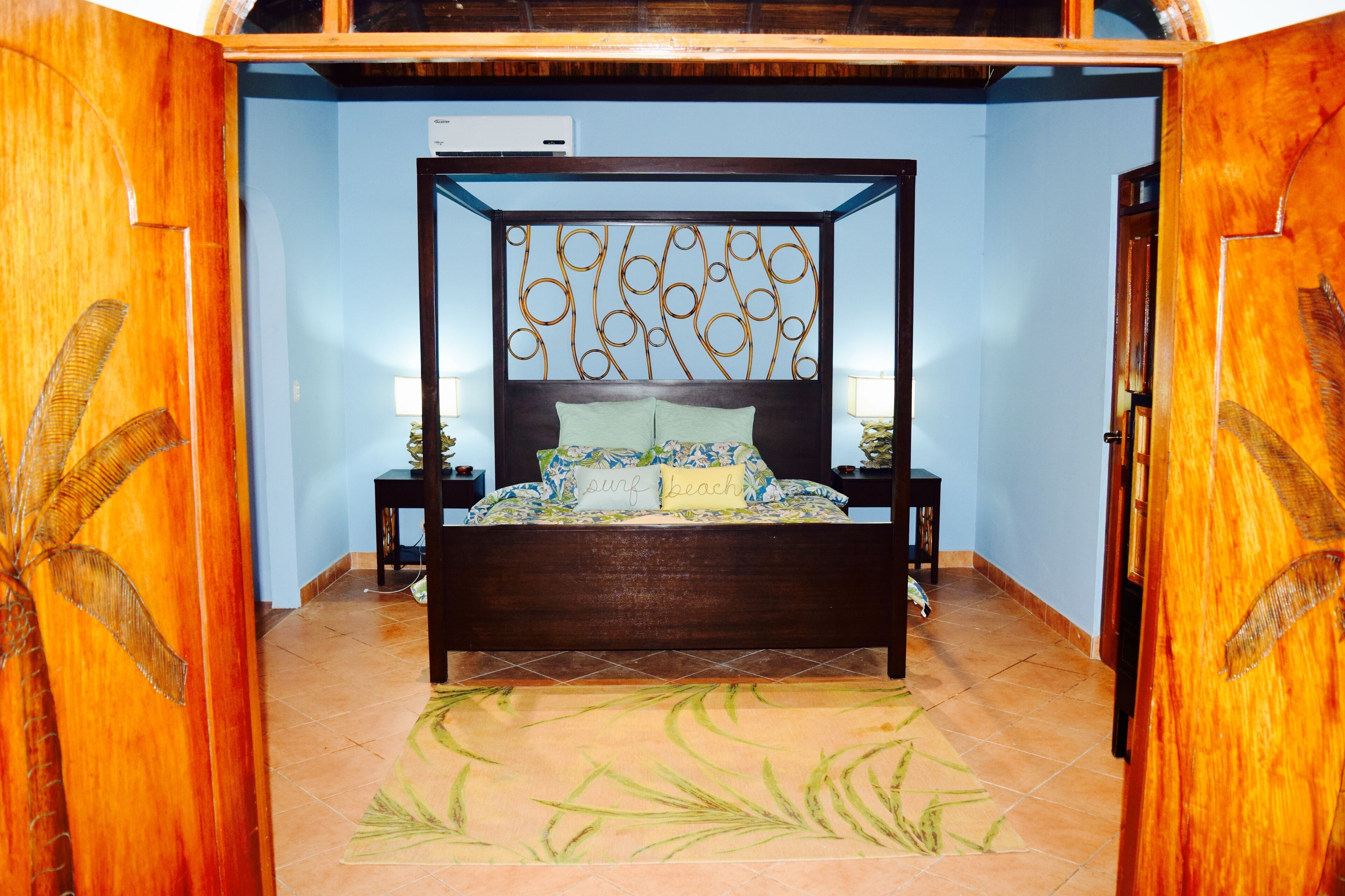 A bedroom with a four-poster bed, a floral-patterned bedspread, and a bamboo-style headboard.