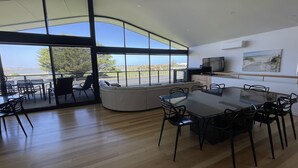 A modern kitchen with a large island, a dining area with a glass table, and a view of the outdoors.