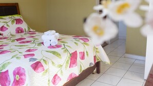 Een bed met een bloemenbedekking, een stapel opgevouwen handdoeken en een betegelde vloer.