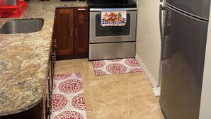 Een compacte keuken met houten kastjes, een RVS magnetron, oven en koelkast.