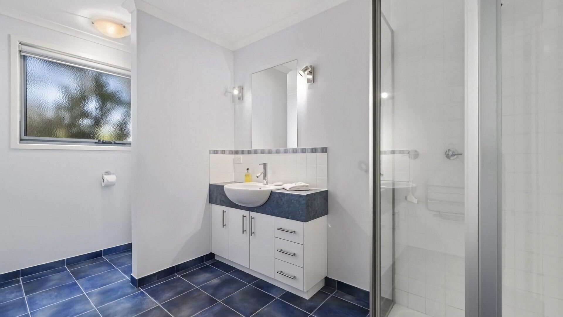 A modern bathroom with a large mirror, a sink, and a shower.