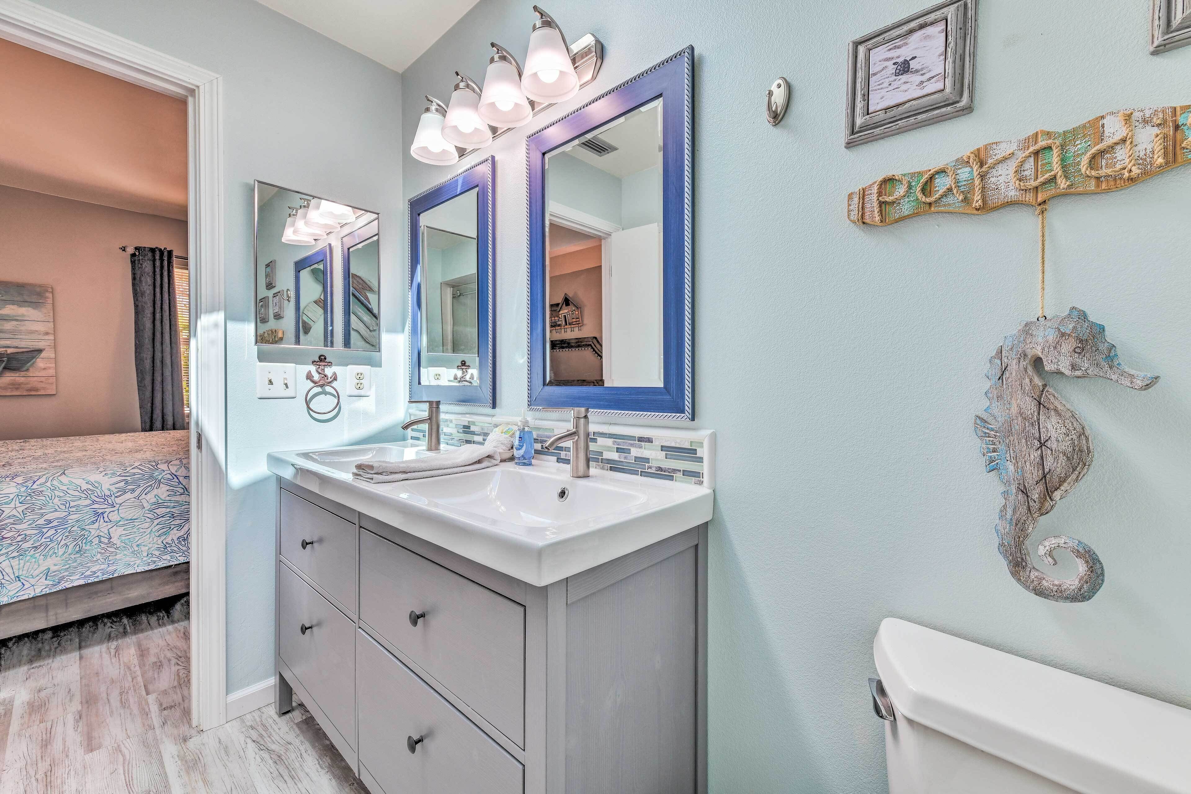 A bathroom with a double vanity, two mirrors, a seahorse decoration, and a toilet.