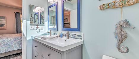 A bathroom with a double vanity, two mirrors, a seahorse decoration, and a toilet.