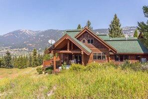 A log cabin with a green roof, a porch, and a satellite dish.