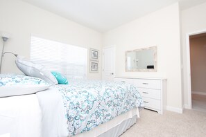 Cozy retreat with a neatly made bed, dresser, and mirror.