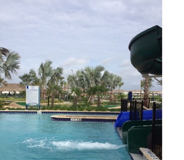 Relax by the pool surrounded by lush palm trees and a fun water slide.