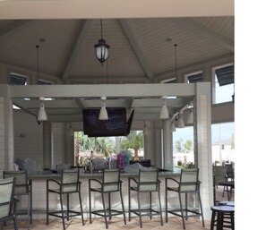 Relax in a casual outdoor space with comfortable seating, pendant lights, and a flat-screen TV.