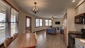 A spacious kitchen with a dining area, wooden furniture, and a ceiling fan. - Point Break Cottage- Steps to Beach- Community Pool & Spa (Buxton)