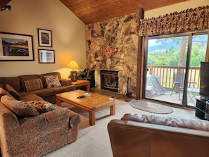 A cozy living room with a stone fireplace, a sofa, a coffee table, and a TV.