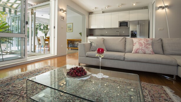 A modern living room with a glass coffee table, a sofa, and a kitchen in the background. - Deluxe apartment Lea with large garden (Split)