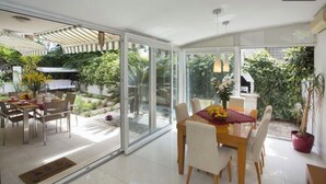 A spacious dining area with a glass wall, a wooden table, and chairs. - Deluxe apartment Lea with large garden (Split)