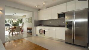 A modern kitchen with white cabinets, stainless steel appliances, and a wooden floor. - Deluxe apartment Lea with large garden (Split)