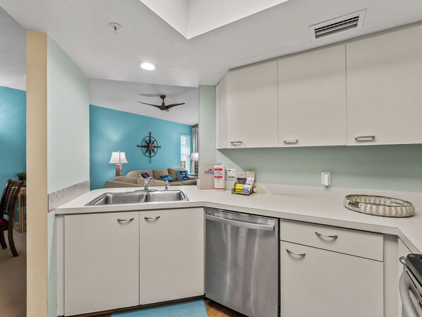 A modern kitchen with a dishwasher, a ceiling fan, and a dining area with a table and chairs.