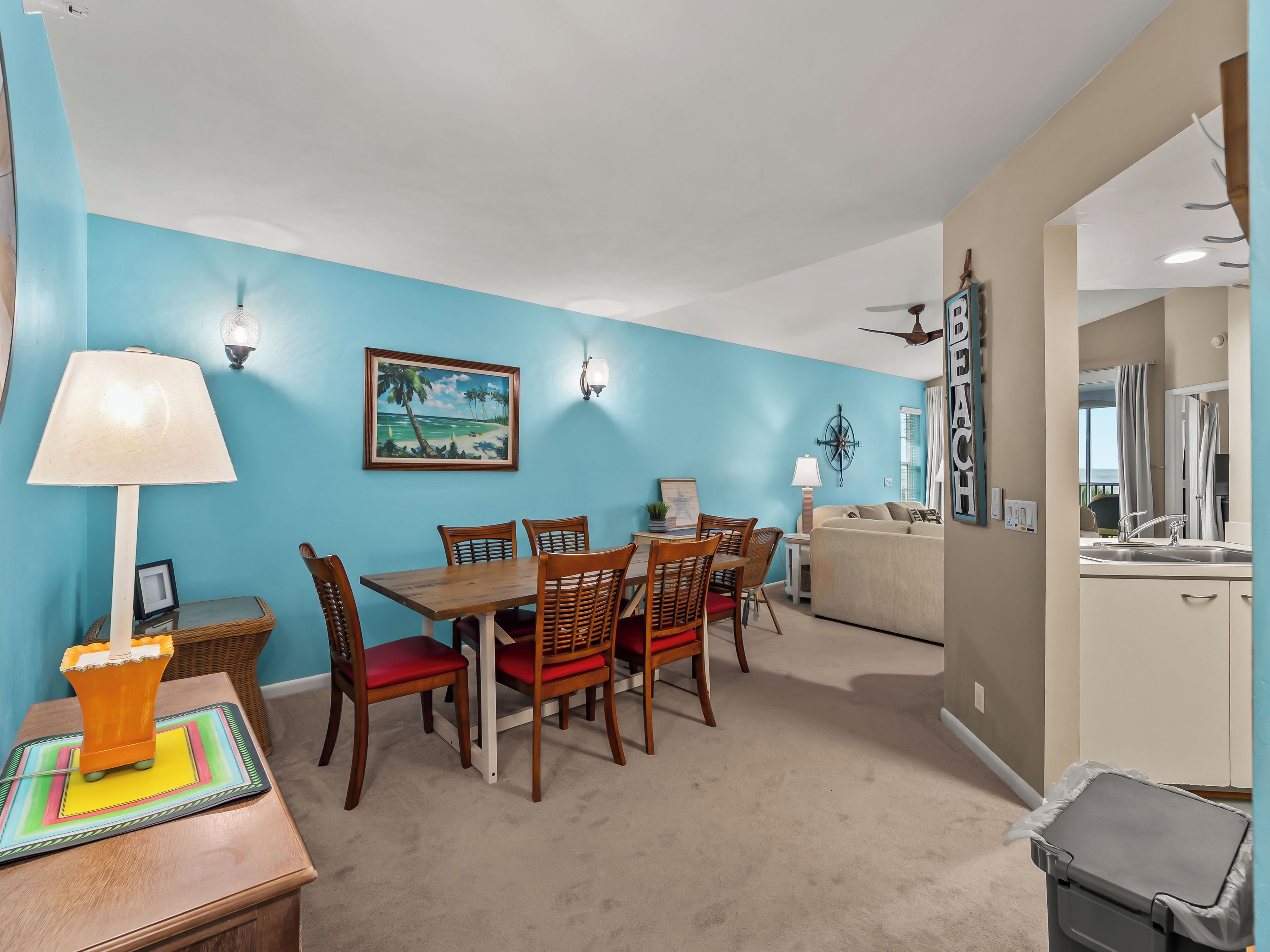 A dining area with a table and chairs, a painting on the wall, and a ceiling fan.