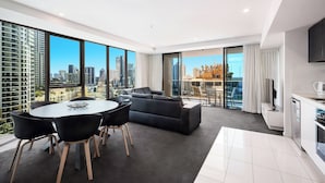 A modern living room with a large window, a sofa, a dining table, and a kitchen area. - H Residences Level 10, Ocean, Free Wi-Fi, Parking, Foxtel (Gold Coast)