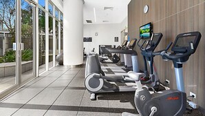 A gym with multiple treadmills and stationary bikes, large windows, and a modern design. - H Residences Level 10, Ocean, Free Wi-Fi, Parking, Foxtel (Gold Coast)