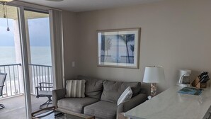 A living room with a sofa, a coffee table, and a view of the ocean. - Magnificent beachfront condo w/ pool & parking at Apollo Condominium (Marco Island)