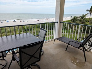 Un balcón con mesa y sillas con vista a la playa.