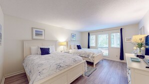 Une chambre avec deux lits, un bureau et une fenêtre avec des rideaux.