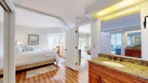 Quarto com cama, mesa de cabeceira e um espelho grande.